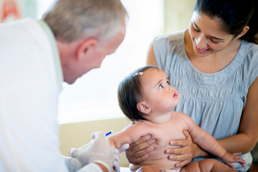 Un profesional de salud administrando una vacuna a un niño con su madre
